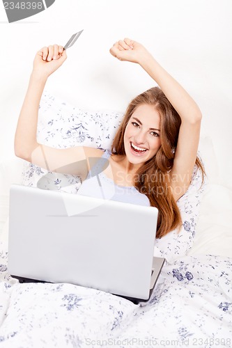 Image of girl sitting in bed and shopping online with credit card