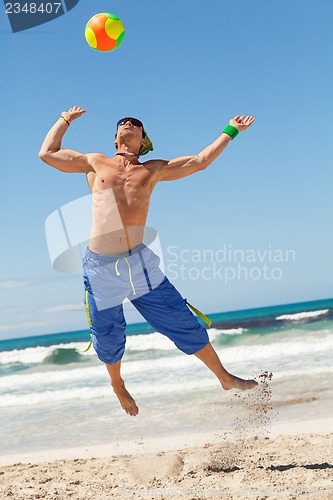 Image of attractive young man playing volleyball on the beach