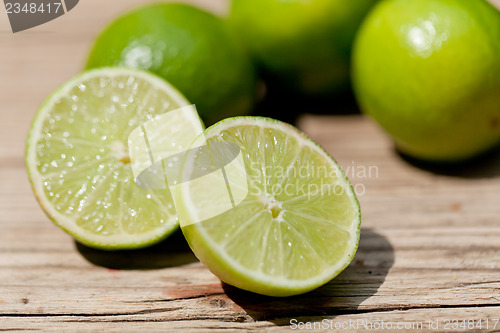 Image of green fresh lime on wooden table macro closeup outdoor