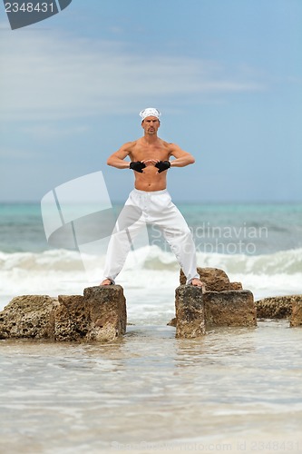 Image of healthy man doing pilates yoga meditation on beach summer