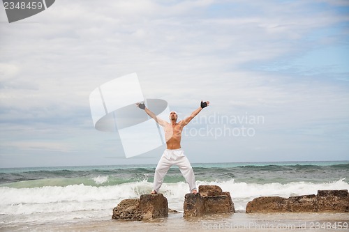 Image of healthy man doing pilates yoga meditation on beach summer