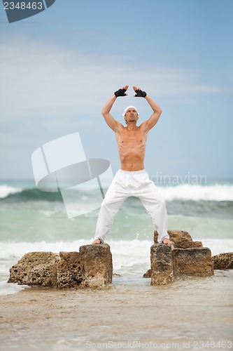 Image of healthy man doing pilates yoga meditation on beach summer