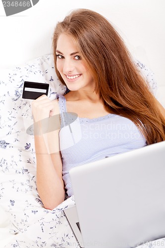 Image of girl sitting in bed and shopping online with credit card