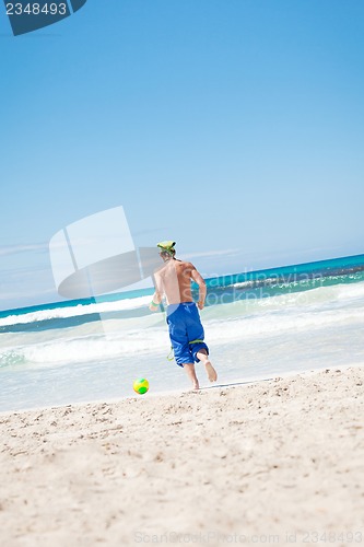 Image of attractive young man playing volleyball on the beach