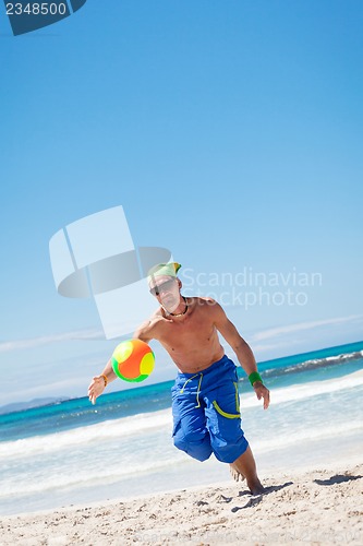 Image of attractive young man playing volleyball on the beach