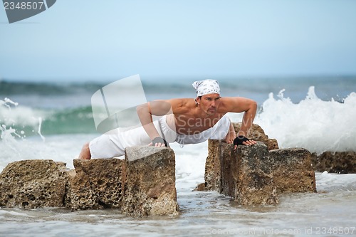 Image of healthy man doing pilates yoga meditation on beach summer