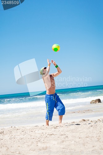 Image of attractive young man playing volleyball on the beach