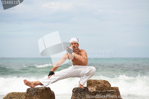 Image of healthy man doing pilates yoga meditation on beach summer