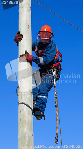 Image of Electrician climbs the pole transmission line