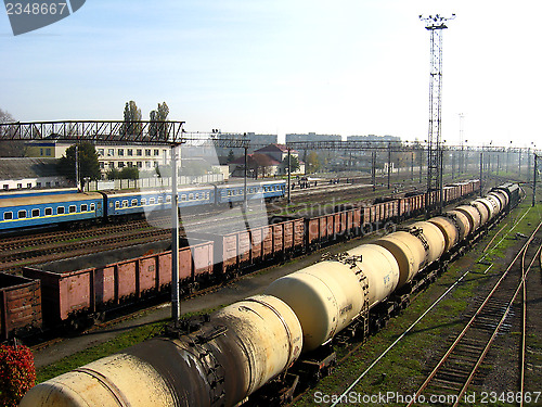 Image of The cars of a freight train and tank trucks