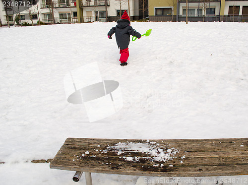 Image of little girl green shovel snow climbs mountain 