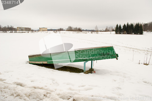 Image of upturned wooden boat snow frozen lake bank winter 