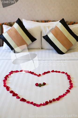 Image of Heart of rose petals laid out on the bed