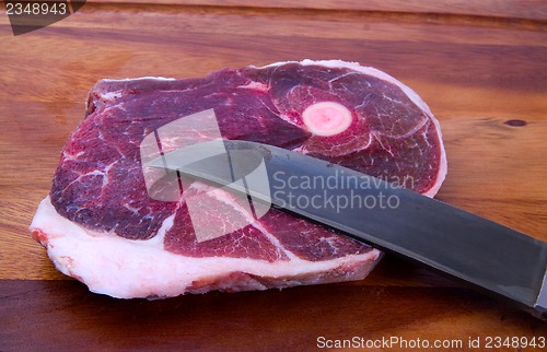 Image of Raw meat with knife on kitchen board