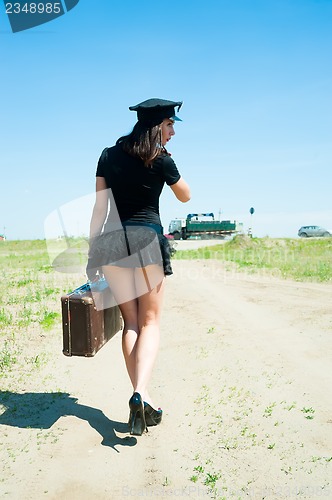Image of Sexy police woman going with old suitcase