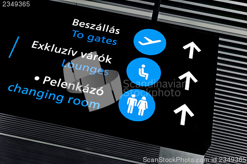 Image of Black airport terminal sign with blue symbols