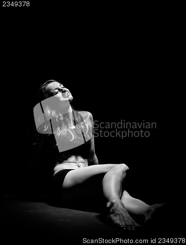 Image of Young muscular woman under bright light