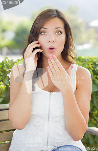 Image of Shocked Young Adult Female Talking on Cell Phone Outdoors
