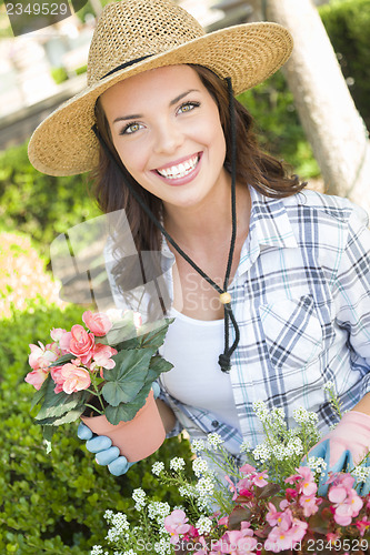 Image of Young Adult Woman Wearing Hat Gardening Outdoors