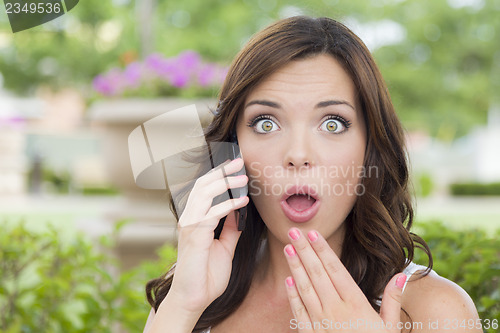 Image of Shocked Young Adult Female Talking on Cell Phone Outdoors