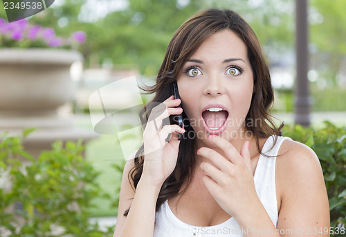 Image of Shocked Young Adult Female Talking on Cell Phone Outdoors