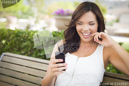 Image of Young Adult Female Texting on Cell Phone Outdoors