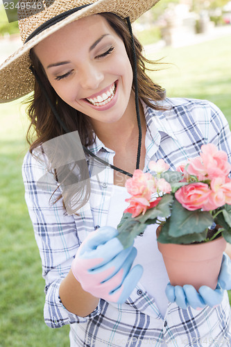 Image of Young Adult Woman Wearing Hat Gardening Outdoors