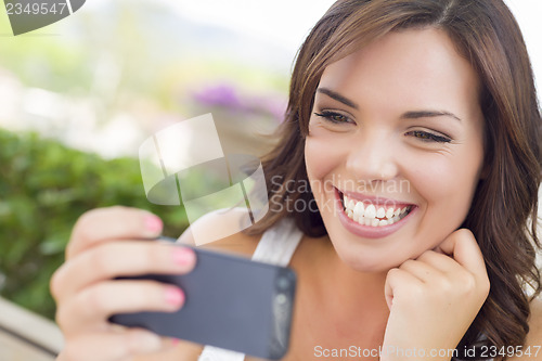 Image of Young Adult Female Texting on Cell Phone Outdoors