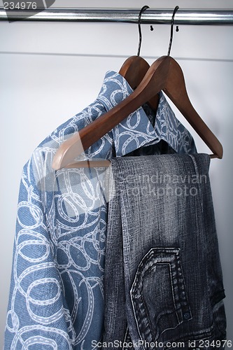 Image of Blue jeans and shirts on wooden hangers