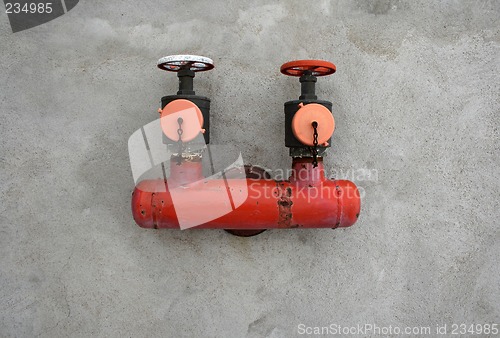 Image of Red iron valve on a concrete wall