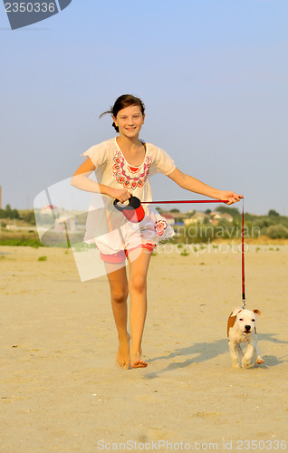 Image of girl running with her dog on the sand 