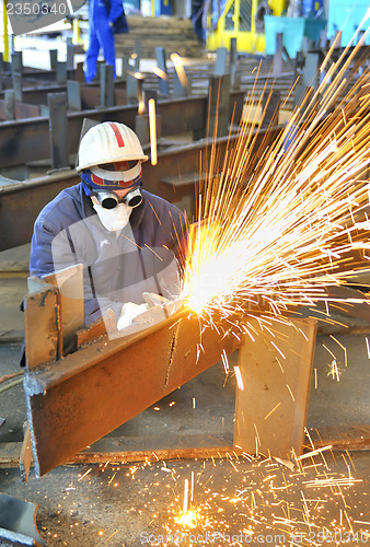 Image of worker using torch cutter to cut through metal