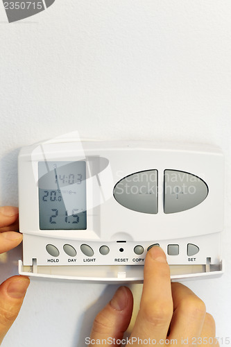 Image of hand pressing button on digital thermostat