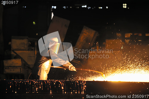 Image of worker using torch cutter to cut through metal 