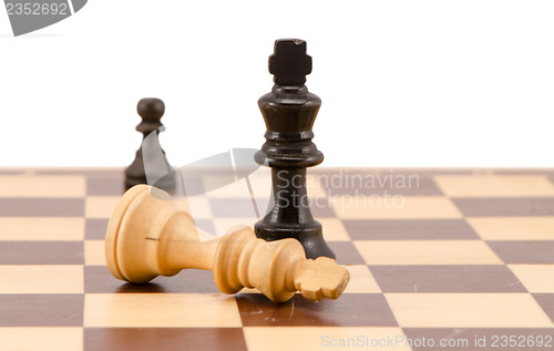 Image of white chess king lie near winner black legs 
