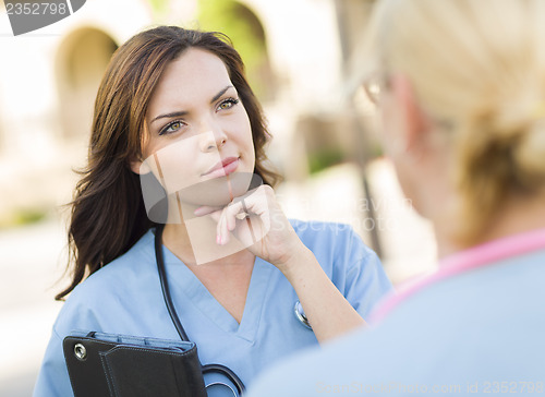 Image of Two Young Adult Female Doctors or Nurses Talking Outside