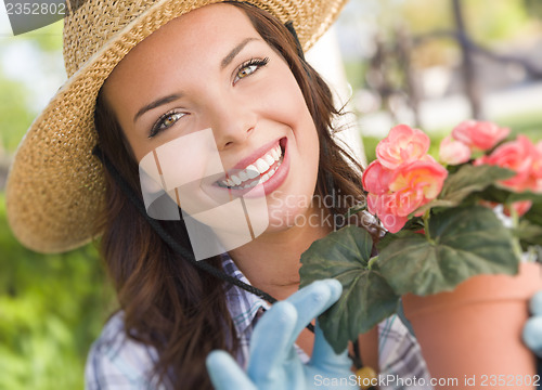 Image of Young Adult Woman Wearing Hat Gardening Outdoors
