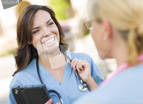 Image of Two Young Adult Female Doctors or Nurses Talking Outside