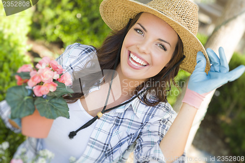 Image of Young Adult Woman Wearing Hat Gardening Outdoors