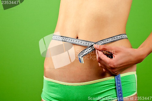 Image of young woman measuring her slim body 