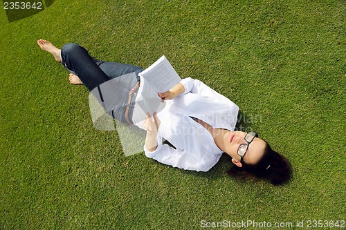 Image of Young woman reading a book in the park
