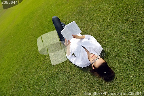 Image of Young woman reading a book in the park