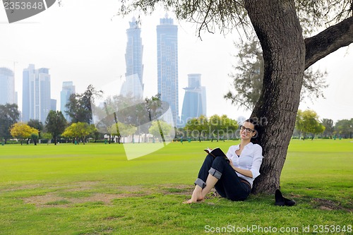 Image of Young woman reading a book in the park