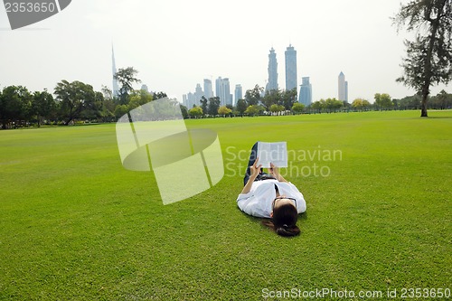 Image of Young woman reading a book in the park