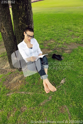 Image of Young woman reading a book in the park