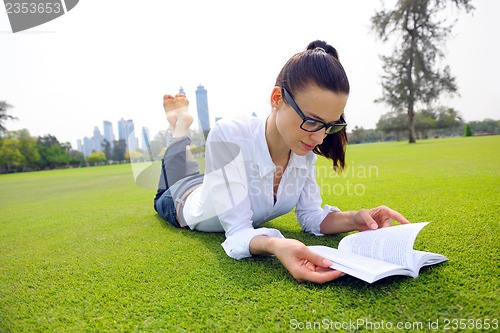 Image of Young woman reading a book in the park