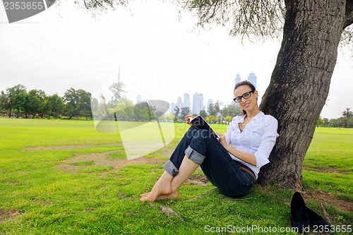 Image of Young woman reading a book in the park