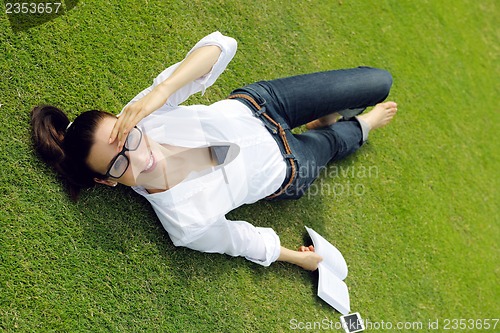 Image of Young woman reading a book in the park