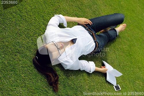 Image of Young woman reading a book in the park