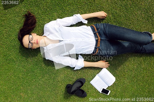 Image of Young woman reading a book in the park